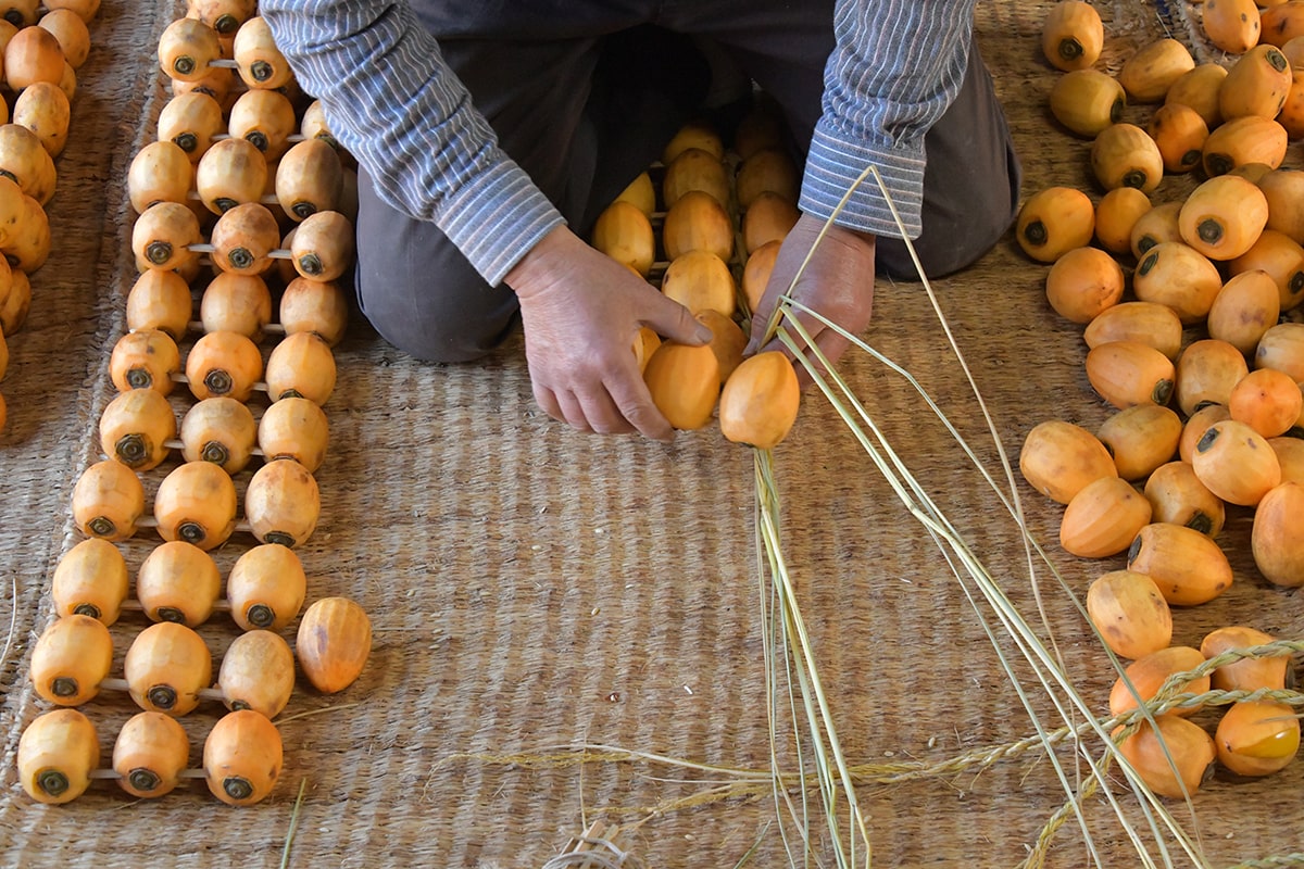 柿10串をワラで編む作業