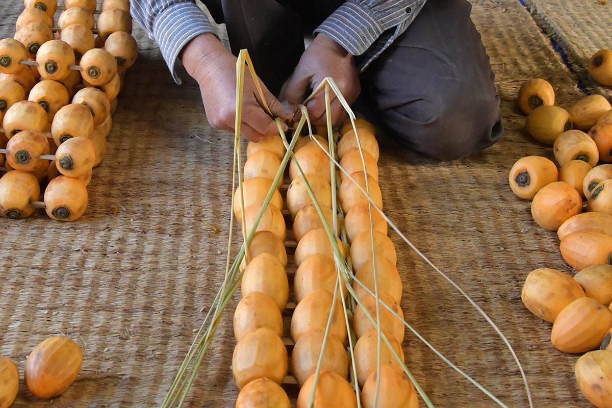 柿10串をワラで編む作業